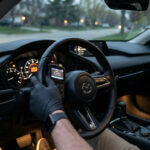 Main gantée utilisant un outil de diagnostic OBD sur le volant d'une voiture Mazda avec le voyant moteur allumé.