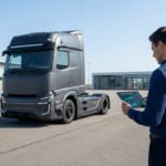 Un homme examine les données de performance d'un camion moderne sur une tablette numérique.