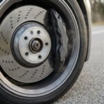 Disque de frein ventilé d'une voiture en mouvement sur une route goudronnée, vu de côté.
