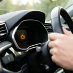 Un conducteur tient le volant alors que le voyant orange du système antipollution est allumé sur le tableau de bord.