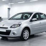 Une Renault Clio 3 grise garée dans un garage automobile lumineux et spacieux.